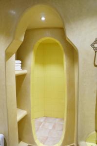 a bathroom with a shower with a yellow tile floor at Dar Amoudou in Ouarzazate