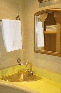 a bathroom with a sink and a mirror and towels at Dar Amoudou in Ouarzazate