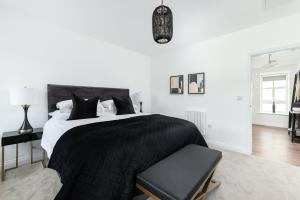 ein weißes Schlafzimmer mit einem schwarzen Bett und einem Stuhl in der Unterkunft The Bronte Bobbin in Haworth