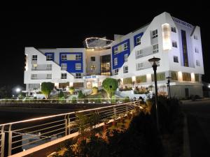 um grande edifício branco à noite com luzes em GOLDEN PARK HOTEL & RESORT em Māldah
