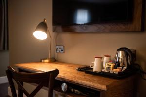 a wooden table topped with a coffee mug and a lamp at The Castle by Innkeeper's Collection in Castleton
