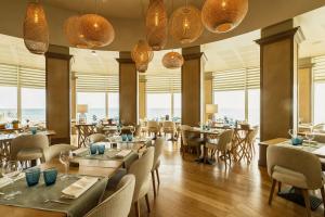 a restaurant with tables and chairs and windows at Alliance Pornic Hôtel Thalasso & Spa in Pornic