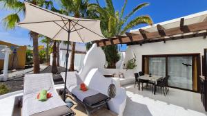 patio z krzesłami, parasolem i stołem w obiekcie Casa EL JARDIN w mieście Morro del Jable