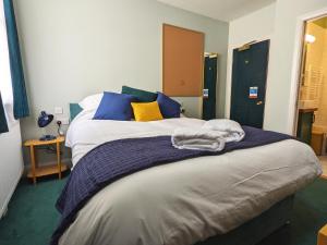 a bedroom with a large bed with blue and yellow pillows at The Stirling Arms Pub & Rooms in Brighton & Hove