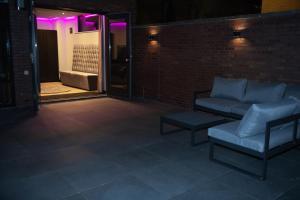 a couch and a stool on a brick wall with purple lights at Royal Suite in 's-Gravenzande