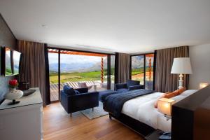 a bedroom with a bed and two chairs and a balcony at Clouds Estate in Stellenbosch +98 photos