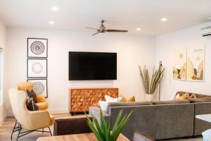 ein Wohnzimmer mit einem Sofa und einem TV an der Wand in der Unterkunft Zen Trail Retreat - New 5 bedroom luxury Condo in St. George