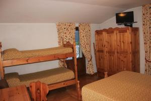 a bedroom with two bunk beds and a bed and a television at Hotel Gufo in Bormio