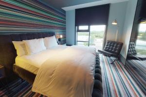 Village Hotel Farnborough في فارنبورو: غرفة نوم بسرير كبير وبجدار مخطط