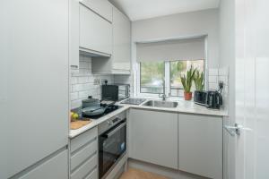 una cocina con armarios blancos y fregadero en Skyline Serviced Apartments - Flat B Rockingham Way en Stevenage