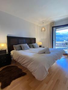 a large white bed in a bedroom with a large window at Ático con vistas increibles a pie de pista y garaje incluido in Sierra Nevada