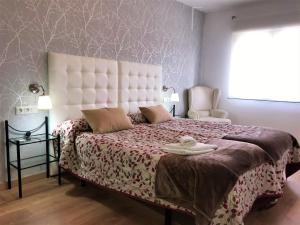 a bedroom with a large bed with a white headboard at Apartamentos Rondaluz in Ronda