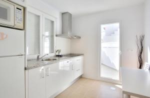 a white kitchen with a sink and a window at Apartamentos Ronda Luz in Ronda