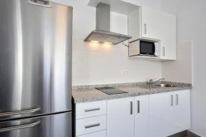 a kitchen with white cabinets and a stainless steel refrigerator at Apartamentos Rondaluz in Ronda