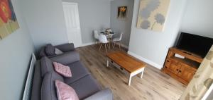 a living room with a gray couch and a table at Stamford - Entire 1 bed cosy home. in Stamford