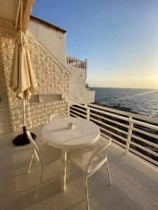 カジャオ・サルバヘにあるLas Barandasの白いテーブルと椅子、海を望むバルコニー