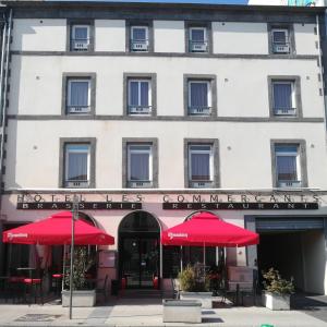 un bâtiment avec des parapluies rouges devant lui dans l'établissement Hotel les Commercants, à Clermont-Ferrand