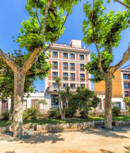 ein Gebäude mit Bäumen davor in der Unterkunft 30º Hotels - Hotel Espanya Calella in Calella