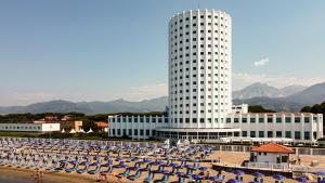 a building with a lot of umbrellas in front of a beach at Villaggio Torre Marina in Marina di Massa