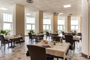 a dining room with tables and chairs and windows at Villaggio Torre Marina in Marina di Massa