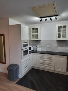 a kitchen with white cabinets and a black counter top at Self Contained studio flat in Winterton Hall in Great Yarmouth
