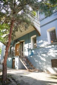 una casa azul con una escalera junto a un árbol en chio's place, en Tiflis