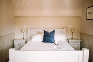 a white bed with a blue pillow on it at George and Dragon in Horsham