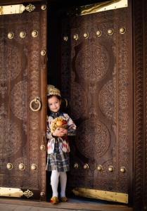a little girl is standing in a wooden door at New Star Boutique hotel - madrasah Muhammad Mahram 1903 in Khiva