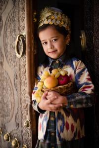 a young girl holding a basket of fruit at New Star Boutique hotel - madrasah Muhammad Mahram 1903 in Khiva