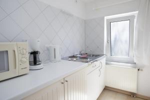 eine weiße Küche mit einer Mikrowelle und einem Fenster in der Unterkunft Ferienanlage Duhnen in Cuxhaven