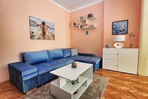 uma sala de estar com um sofá azul e uma mesa em Colorful apartment em Sófia