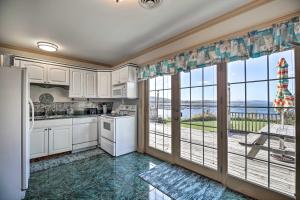 a kitchen with white cabinets and a large window at Waterfront Lake Champlain Home with Fire Pit! in Saint Albans Bay