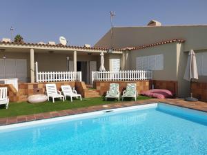 einen Pool mit zwei Stühlen und ein Haus in der Unterkunft Bungalow Paraiso El Mar 3 in San Agustín