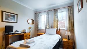 a bedroom with a bed and a desk and a window at Pickwicks Guest House in Oxford