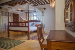 a bedroom with a canopy bed and a wooden table at MANDA ISLAND Private Villa in Lamu