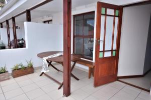eine offene Tür zu einem Balkon mit einem Tisch und einem Stuhl in der Unterkunft Cyprus Manor 12 in Mossel Bay