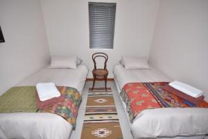 two twin beds in a room with a chair at Cyprus Manor 12 in Mossel Bay