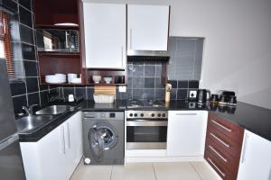 a kitchen with white cabinets and a washing machine at Cyprus Manor 12 in Mossel Bay