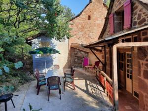 eine Terrasse mit einem Tisch und Stühlen sowie ein Gebäude in der Unterkunft grange rénovée en pleine nature in Valady