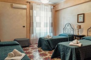 a hotel room with two beds and a window at B&B Elvira Al Duomo in Monreale