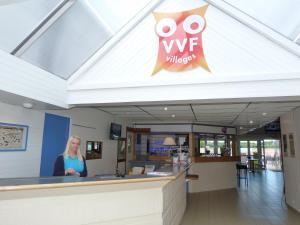 a woman standing at the counter of a wfc restaurant at VVF Les Plages de Guérande La Turballe in La Turballe