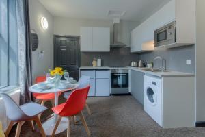 eine Küche mit einem Tisch, Stühlen, einer Spüle und einem Herd in der Unterkunft Remaotel Seafield Court Apartments in Great Yarmouth