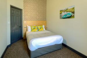 a small bedroom with a bed with yellow pillows at Remaotel Seafield Court Apartments in Great Yarmouth