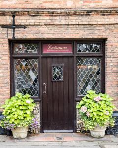 a building with a wooden door and two potted plants at The Red Lion Eaton in Norwich