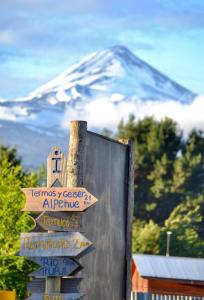 um sinal em frente a uma montanha coberta de neve em Hostal siete colores, Melipeuco em Melipeuco