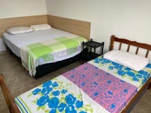 a bedroom with two beds and a table at Apto Guarujá - Asturias in Guarujá