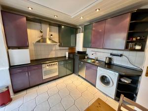eine Küche mit lila Schränken und einer Waschmaschine in der Unterkunft Purple Kitchen - Apartment mit großer Wohnküche in Bremerhaven
