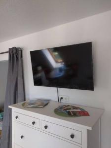 a white dresser with a flat screen tv on a wall at Ostsee, wunderschöne Wohnung mit Meerblick in Harrislee