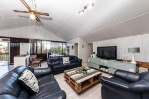 a living room with black leather furniture and a flat screen tv at Fralande Self Catering Units in Pretoria