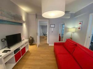 uma sala de estar com um sofá vermelho e uma televisão em Domus Gaudens Luxury Apartment em Taormina
